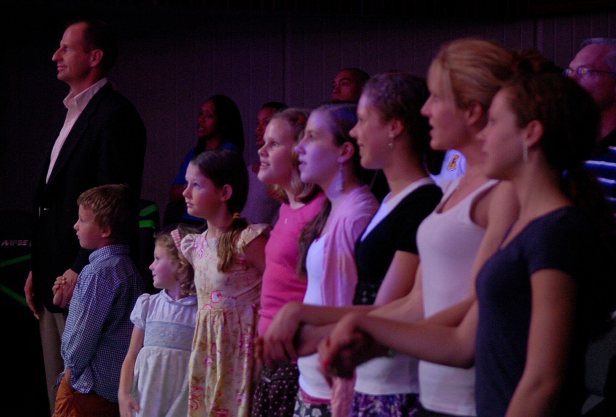 U.S. Air Force Col. Corey Martin, 18th Wing vice commander, and his family stand with the family of U.S. Air Force Brig. Gen. Matthew Molloy, 18th Wing commander, while the Tops in Blue 2011 cast performs their closing song "Proud to be an American" by Lee Greenwood at the Keystone Theater on Kadena Air Base, Japan, Nov. 17, 2011. The Rhythm Nation 2011 world tour brings together some of the most influential entertainers of the past and present, along with a sample of music from each of the most popular genres of American music. (U.S. Air Force photo by Airman 1st Class Tara A. Williamson/Released)