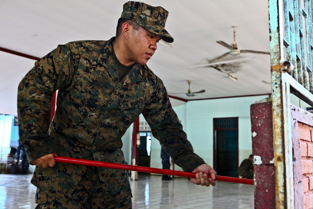 U.S. Marine Cpl. Wyethpaul N. Yadao scrubs dirt left from flood water off the wall inside of the Sanamchai School in Lop Buri, Thailand, Nov. 20, 2011. Yadao is an information systems technician assigned to the III Marine Expeditionary Force flood relief command element. 