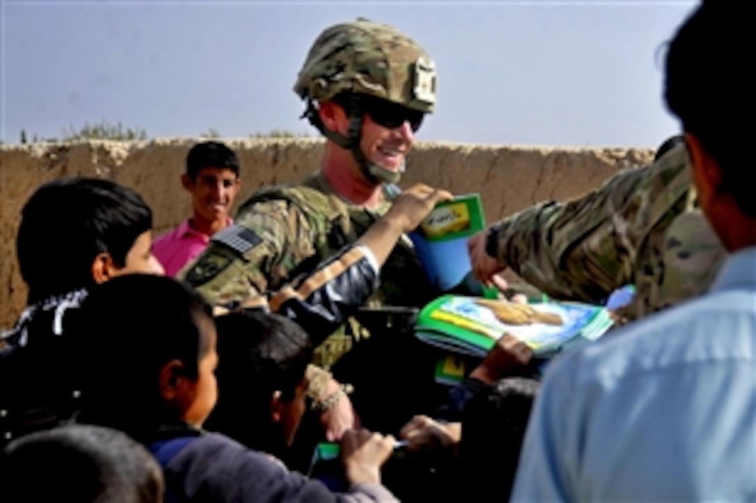 U.S. Navy Lt. j.g. Will Parker, a Provincial Reconstruction Team Farah member, hands out Sada-e Azadi magazines while other members check on the quality of Nawbahar Road in the Khak-e Safeyd district in Afghanistan's Farah province, Nov. 16, 2011. Team members conduct quality assurance checks on road projects to ensure that contractors meet the construction requirements outlined by the team and government officials.