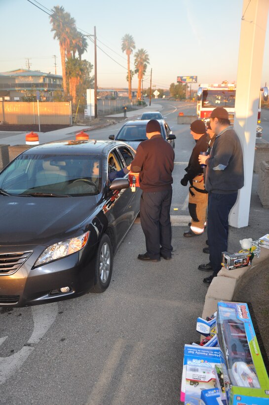 Firefighters aboard Marine Corps Logistics Base Barstow stand at the front gate collecting money and toys for the Toys for Tots campaign during “Toys for Tots Tuesdays” Nov. 22.