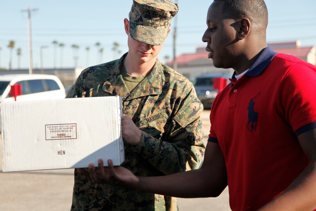 Cpl. Makenzy Simeon, embarkation specialist, delivers a turkey to Cpl. Joshua B. Kelso, tech controller, both with the 15th Marine Expeditionary Unit, which was donated to him and the other Marines and sailors at their unit, Nov. 22. Operation Homefront, in coordination with Albertsons and the Junipero Serra High School water polo team in San Juan Capistrano, Calif., donated 19 prepackaged meals and an additional 40 turkeys to the 15th MEU for Thanksgiving. The turkey boxes include a 10-12 pound turkey, mashed potatoes, stuffing and gravy that can feed up to eight people. (U.S. Marine Corps photo by Cpl. John Robbart III)