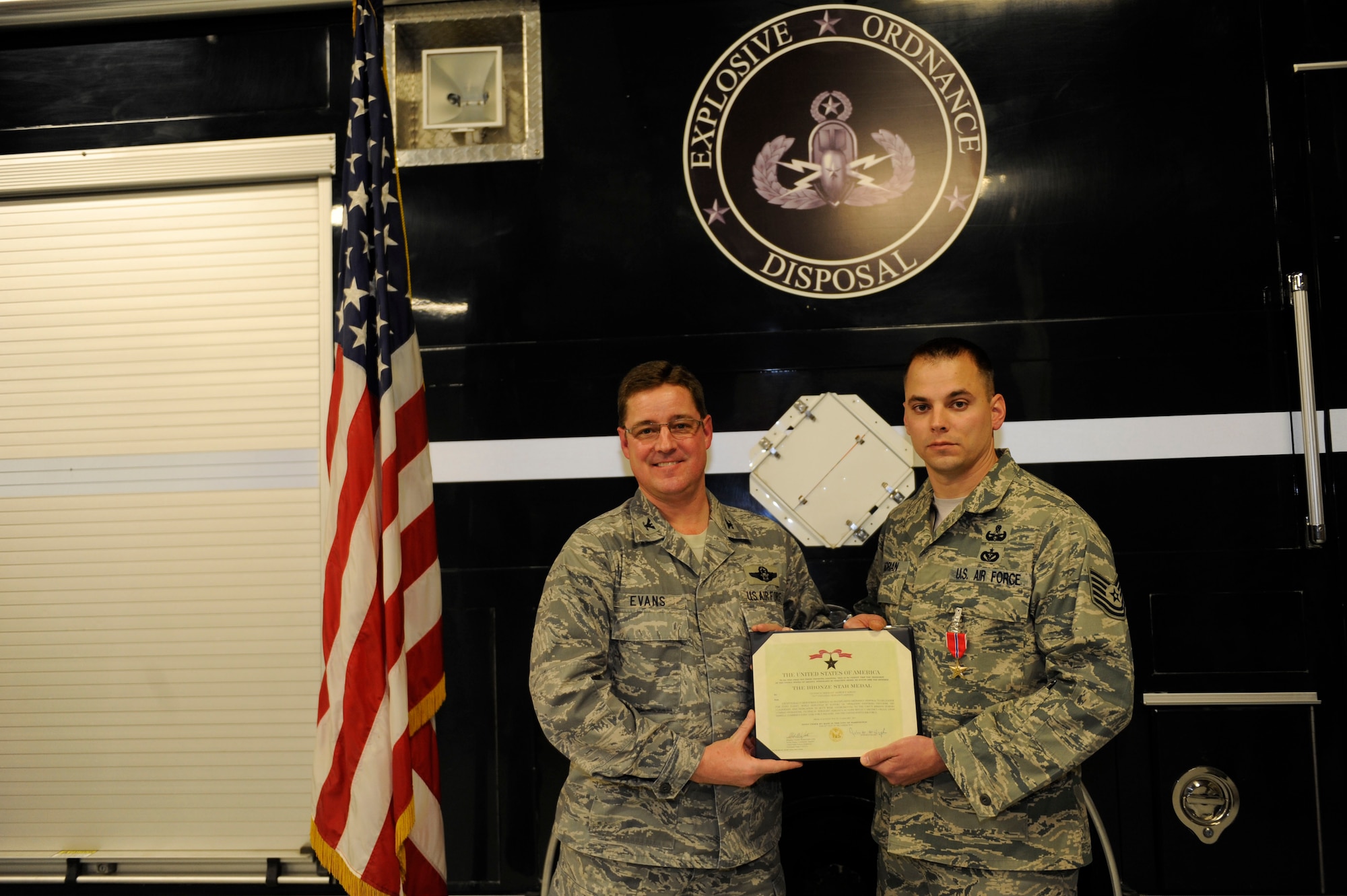 Col. Robert Evans awards Tech Sgt. Andrew Adrian the Bronze Star in the 673rd Explosive Ordinance Disposal shop, Joint Base Elmendorf-Richardson, Alaska Nov. 18, 2011. Adrian disarmed more than 15 improvised explosive devices during his deployment in support of Operation Enduring Freedom in Afghanistan. Evans is the 673rd Air Base Wing and Joint Base Elmendorf-Richardson commander. Adrian is an Explosive Ordinance Disposal team leader. (U.S. Air Force photo/Staff Sgt Robert Barnett)