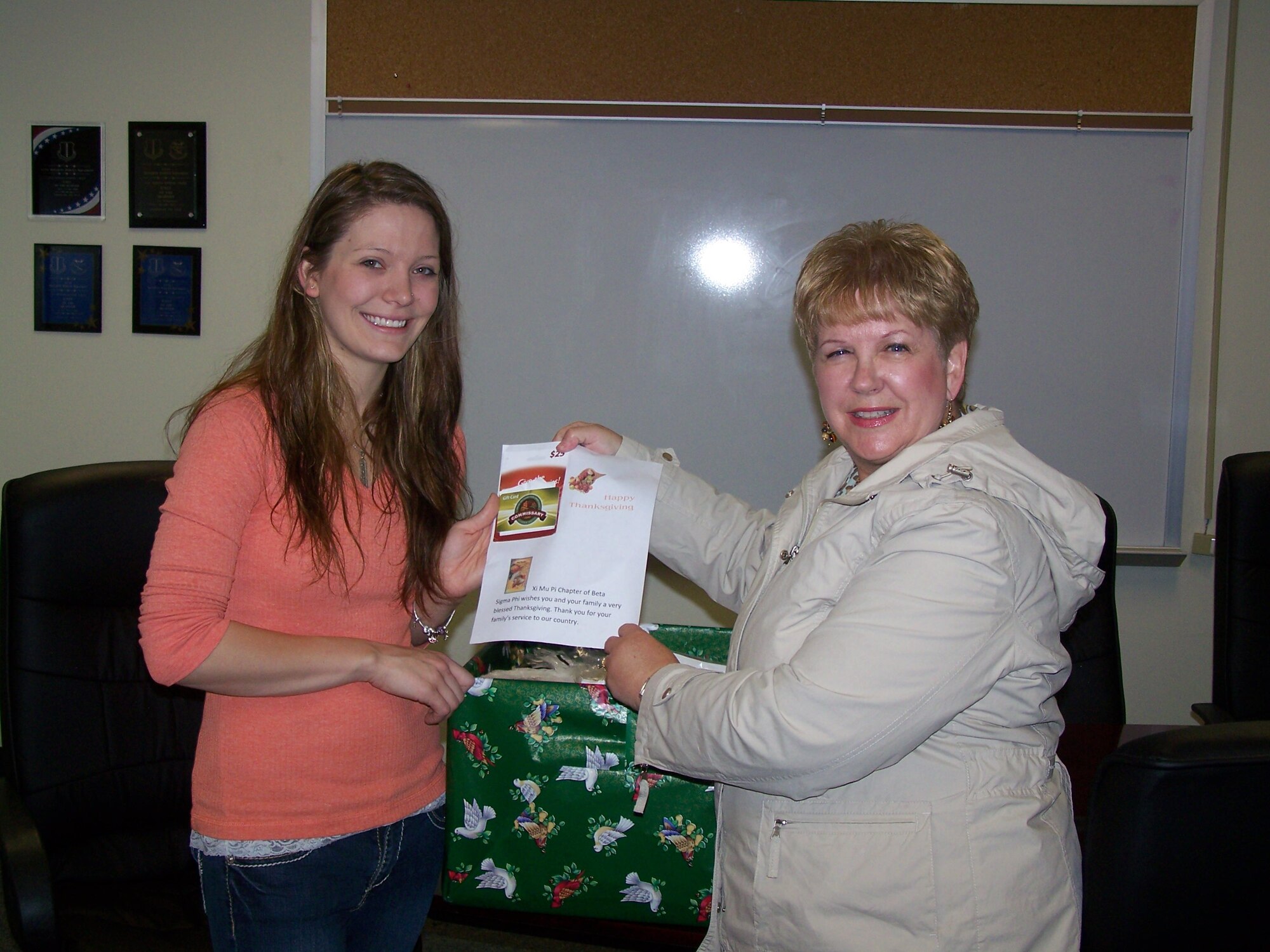 GOODFELLOW AIR FORCE BASE, Texas -- Marilyn Stewart, Child Development Center Assistant Director, right, presents a holiday gift basket to Tara Port. Port’s fiancé Tech. Sgt. Ray Hagemeister, 17th Training Wing Security Forces member, is currently deployed. Sergeant Hagemeister also left behind their 1 year old daughter Reagan. Stewart, who is a member of the Xi Mu Pi Chapter of Beta Sigma Phi, an international social/service sorority, wanted to provide a Thanksgiving meal for a family of a deployed servicemember from Goodfellow. (Courtesy photo)