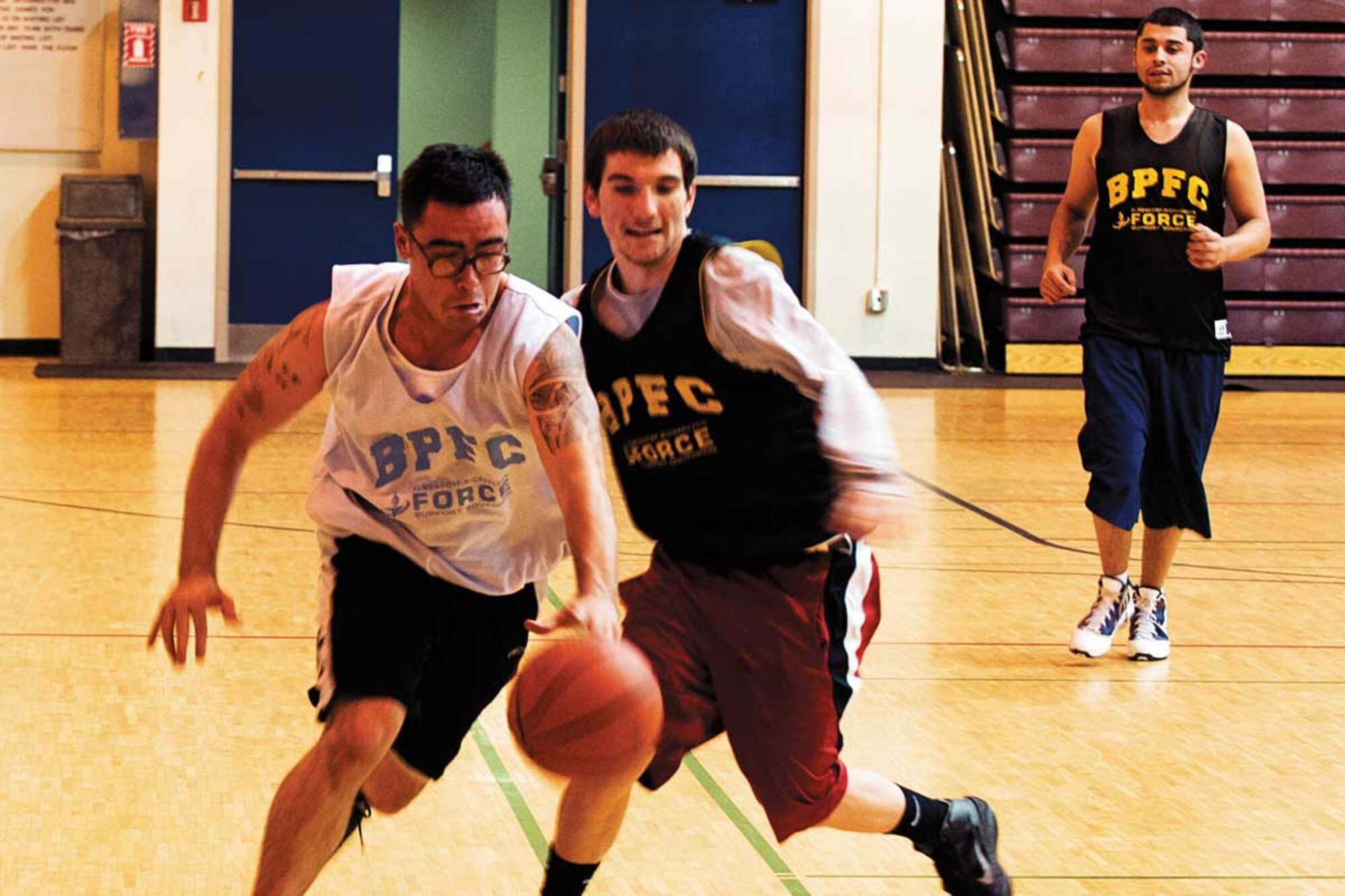 Pfc. Justuce Guerrero, B Company, 3rd Battalion, 509th Infantry Regiment, drives past  Anthony Urzi, military family member, during an intramural basketball game at Buckner Physical Fitness Center on Joint Base Elmendorf-Richardson Monday night. (U.S. Air Force photo/Staff Sgt. Zachary Wolf)
