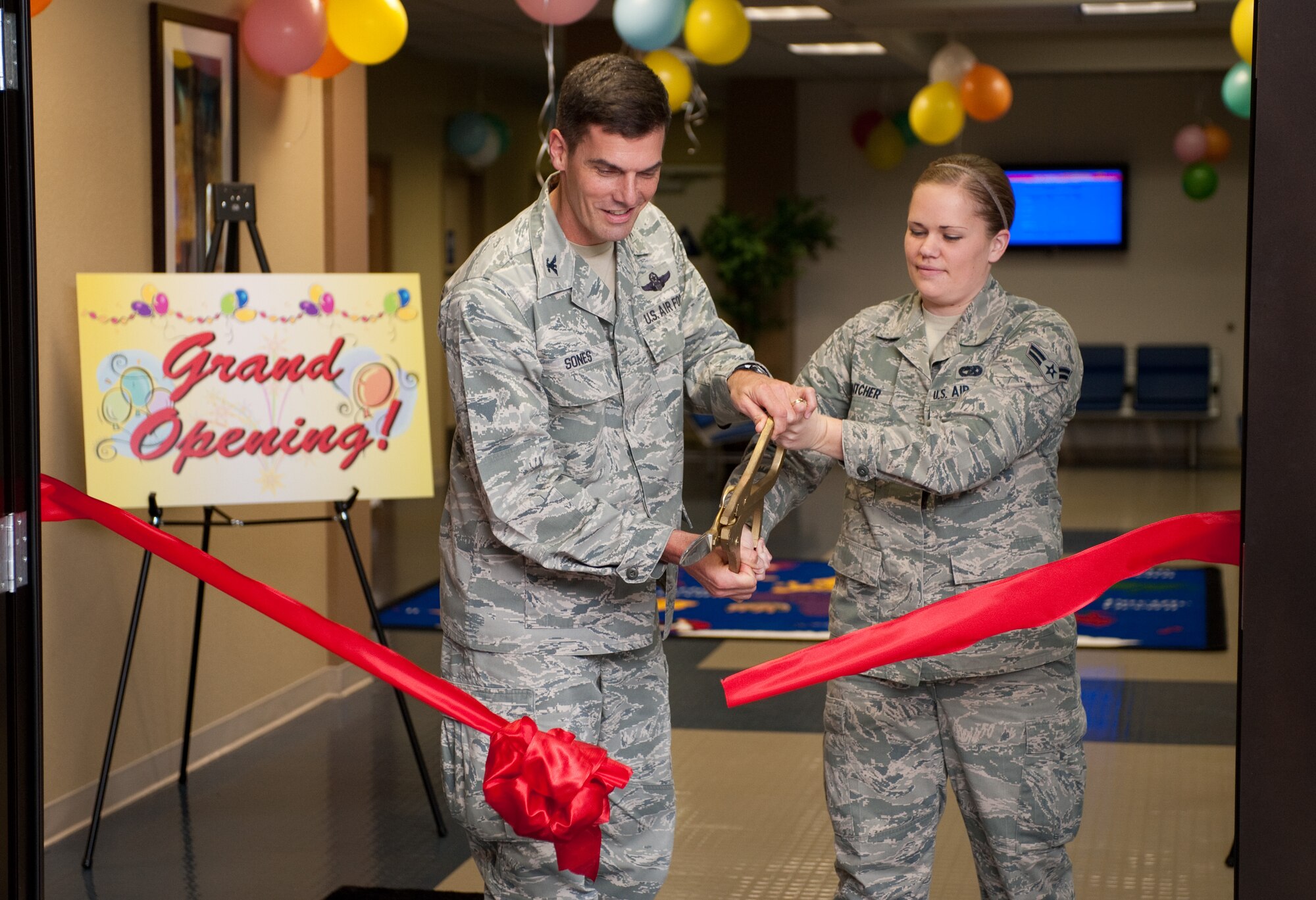 Col. Dwight Sones, 60th Air Mobility Wing commander, and Airman 1st Clas Brooke Dutcher, 60th Aerial Port Squadron, officially open Travis' passenger terminal family lounge. (U.S. Air Force photo/Ken Wright)