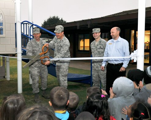 RAF MILDENHALL, England - Col. Kyle Voigt, 100th Air Refueling Wing vice commander, and Col. David Doe, 100th Mission Support Group commander, cut the ribbon during an opening ceremony for a new playground at the Child Development Center here Nov. 22, 2011. The playground, featuring castle-themed play equipment, will be used by pre-schoolers, ages 3 to 5 years. (U.S. Air Force photo/Senior Airman Jerilyn Quintanilla)