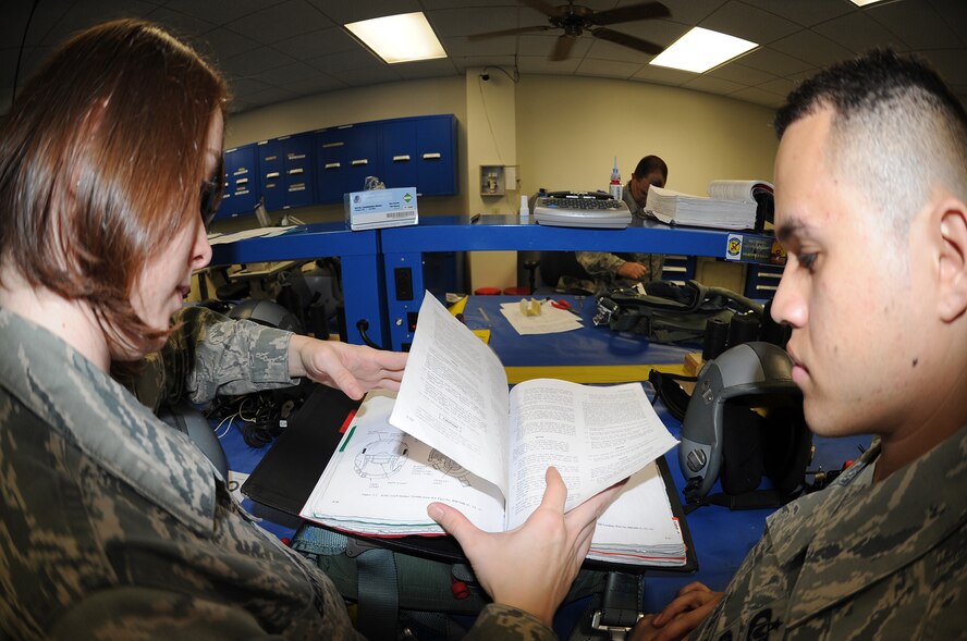 Staff Sgt. Jonathan Rivera and Senior Airman Emily Bertini, 334th Fighter Squadron aircrew flight equipment craftsman and journeyman, review a technical order while performing a 30-day inspection at Seymour Johnson Air Force Base, N.C., Nov. 22, 2011. The inspection will be performed periodically ensuring the aircrew equipment is serviceable. Rivera hails from Vega Alta, Puerto Rico and Bertini hails from Springtown, Texas. (U.S. Air Force photo by Senior Airman Gino Reyes)