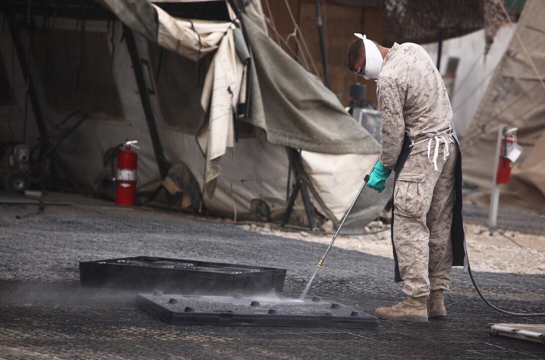 A Marine attached to the sort lot aboard Camp Leatherneck, Afghanistan, cleans a piece of a storage container that will later be used to house excess gear and equipment as part of Operation Clean Sweep, Nov. 24. In its first few days, this operation has identified roughly 2.3 million dollars worth of excess gear and equipment that will eventually be shipped back the United States. (U.S. Marine Corps Photo by Cpl. Michael Augusto)