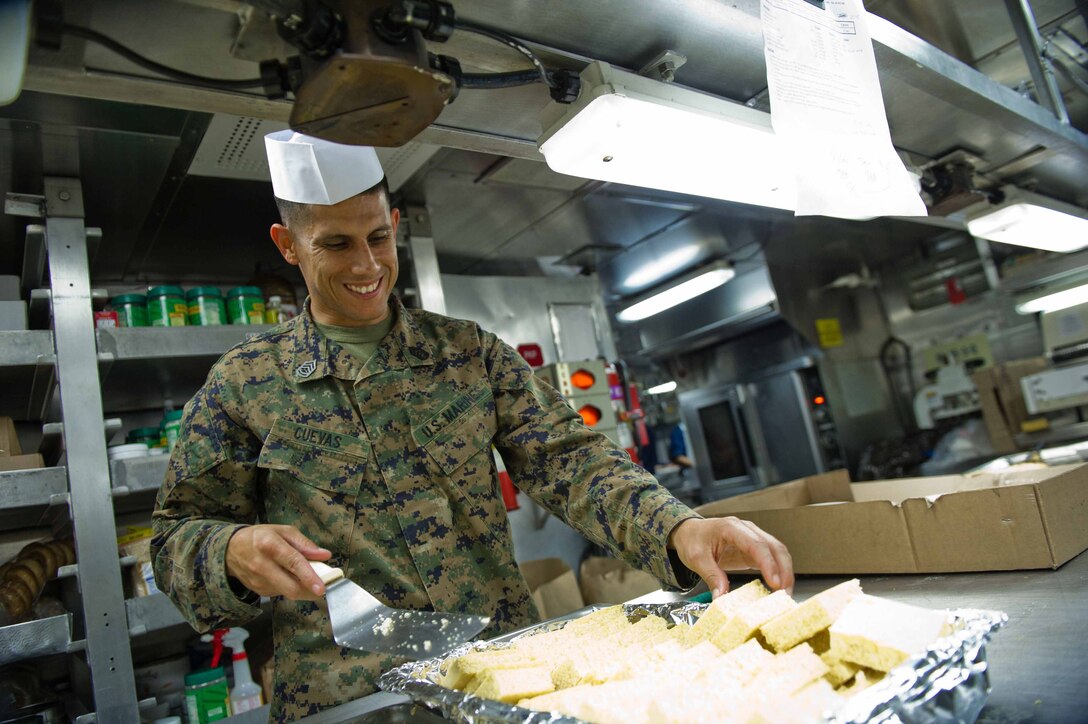 Gunnery Sgt. Anton J. Cuevas cuts corn bread during a Thanksgiving Day celebration aboard USS Pearl Harbor here Nov. 24. Cuevas, a Fayetteville, N.C., native is 32 and serves as the weapons platoon sergeant for Company K. Company K is one of three rifle companies with Battalion Landing Team 3/1. The battalion is the ground combat element for the 11th Marine Expeditionary Unit, which embarked USS Makin Island, USS New Orleans and USS Pearl Harbor in San Diego Nov. 14 beginning a seven-month deployment to the Western Pacific and Middle East regions.