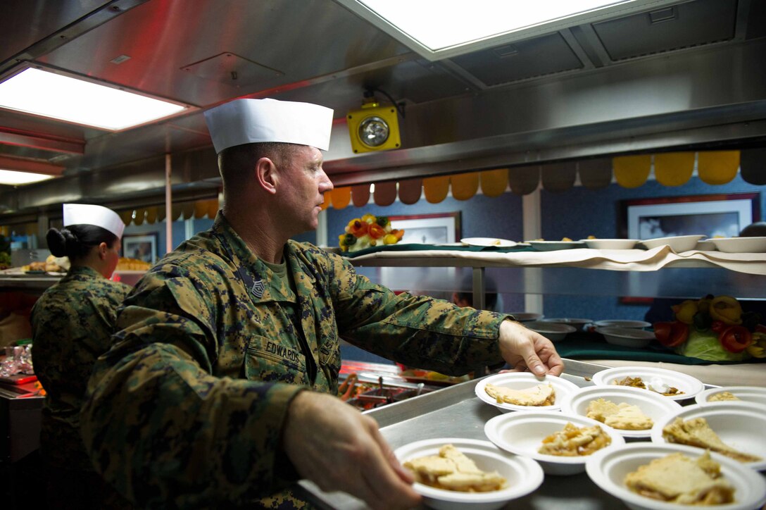 First Sgt. Michael P. Edwards of Company K refills dessert during a Thanksgiving Day celebration aboard USS Pearl Harbor here Nov. 24. Company K is one of three rifle companies for Battalion Landing Team 3/1. The battalion is the ground combat element for the 11th Marine Expeditionary Unit, which embarked USS Makin Island, USS New Orleans and USS Pearl Harbor in San Diego Nov. 14 beginning a seven-month deployment to the Western Pacific and Middle East regions. Edwards is 41 and hails from Rome, N.Y.