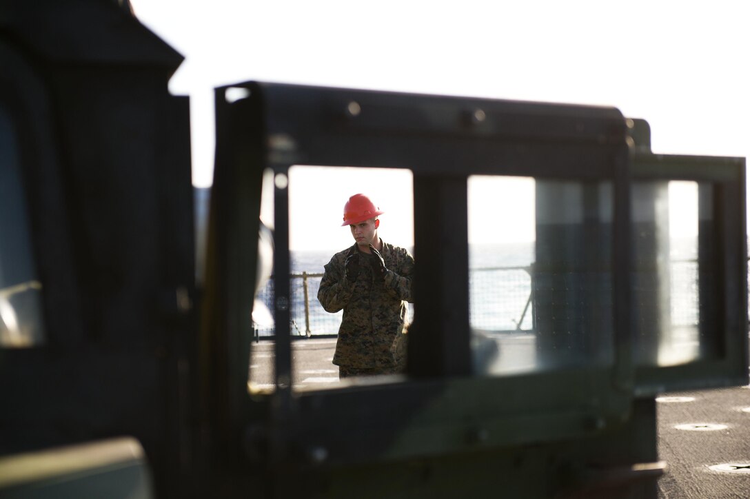 Motor transport operator Lance Cpl. Craig D. Williams provides ground guidance as a humvee backs up aboard USS Pearl Harbor here Nov. 25. Williams, a Lucasville, Ohio, native, is 22 and serves with Combat Logistics Battalion 11. The battalion is the combat logistics element for the 11th Marine Expeditionary Unit, which embarked USS Makin Island, USS New Orleans and USS Pearl Harbor in San Diego Nov. 14 beginning a seven-month deployment to the Western Pacific and Middle East regions.