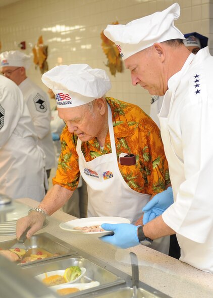Mr. Duward Swanson, a Hickam Field survivor, and Gen. Gary North, Pacific Air Forces commander, serve slices of ham to Hickam Airmen at the Hale Aina Dining Facility at Joint Base Pearl Harbor-Hickam, Hawaii, Nov. 24. Gen. North and PACAF senior leaders, Air Force Civilian Advisory Council and Friends of Hickam, where all on hand to help serve and celebrate Thanksgiving Day with Airmen and their family and friends. (U.S. Air Force photo/Tech. Sgt. Jerome S. Tayborn/Released)