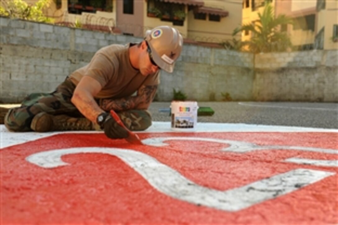 U.S. Navy Petty Officer 2nd Class Barron Montowski paints the Navy Mobile Construction Battalion 23 logo on the basketball court at Rafaela Santaella Basic School in Santo Domingo, Dominican Republic, Nov. 23, 2011. Montowski is a steelworker assigned to NMCB 23, which completed a three-week project at the school as part of an annual deployment of U.S. ships to the U.S. Southern Command's area of responsibility in the Caribbean and Latin America.