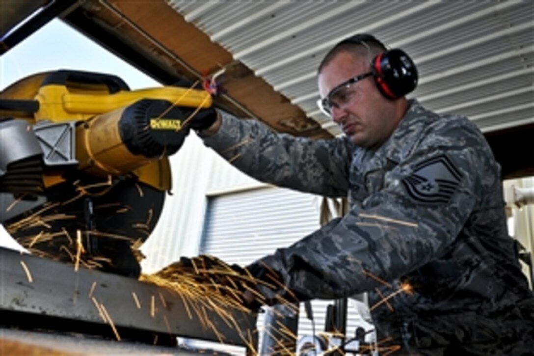 U.S. Air Force Senior Master Sgt. Kurt Huver cuts a piece of metal tubing to be used for fabricating poles for telephone boxes in Commando Village at an undisclosed location in Southwest Asia Nov. 23, 2011. Huver is a mission support specialist with the 386th Expeditionary Civil Engineer Squadron.