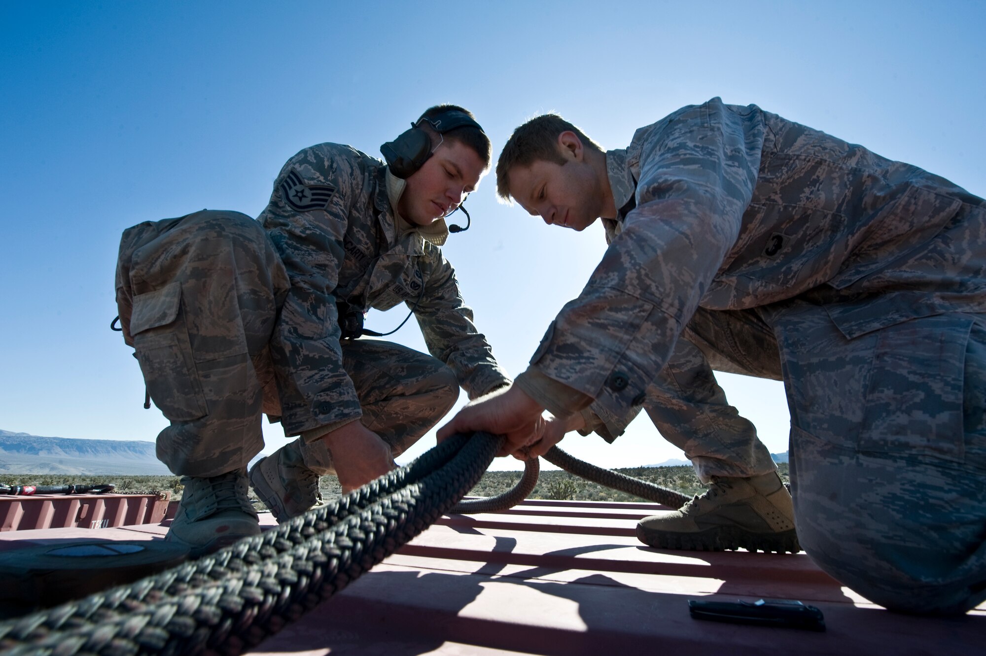 U.S. Air Force Airmen, 820th RED HORSE Squadron airborne flight, take a knee as a CH-47 Chinook from the Army National Guard, Stockton, Calif., recovers an aircraft part during a peacetime operation Nov. 9, 2011, in the Nevada Test and Training Range. The sling load training and air assault certification of 820th RHS airborne flight Airmen proved crucial in the success of the quick-response operation. (U.S. Air Force photo by Airman 1st Class Daniel Hughes/Released)
