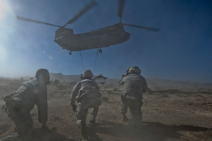 U.S. Air Force Airmen, 820th RED HORSE Squadron airborne flight, take a knee as a CH-47 Chinook from the Army National Guard, Stockton, Calif., recovers an aircraft part during a peacetime operation Nov. 9, 2011, in the Nevada Test and Training Range. The sling load training and air assault certification of 820th RHS airborne flight Airmen proved crucial in the success of the quick-response operation. (U.S. Air Force photo by Airman 1st Class Daniel Hughes/Released)
