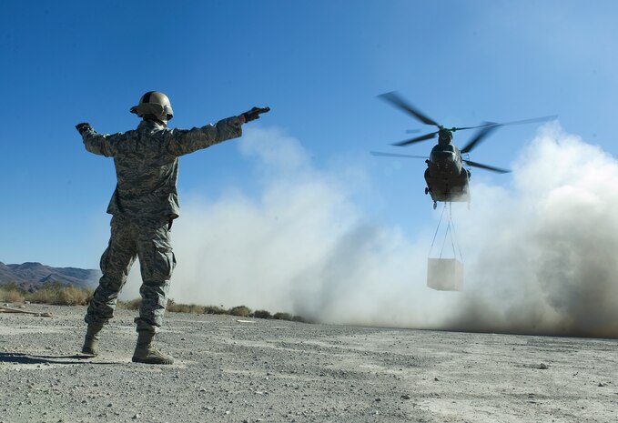 U.S. Air Force Master Sgt. Guenther Bogensperger, 820th RED HORSE airborne flight airborne water and fuels systems maintenance superintendent, guides in a CH-47 Chinook from the Army National Guard, Stockton, Calif., to a designated drop site during a peacetime operation Nov. 9, 2011, in the Nevada Test and Training Range. The sling load training and air assault certification of 820th RHS airborne flight Airmen proved crucial in the success of the quick-response operation. (U.S. Air Force photo by Staff Sgt. Christopher Hubenthal/Released)