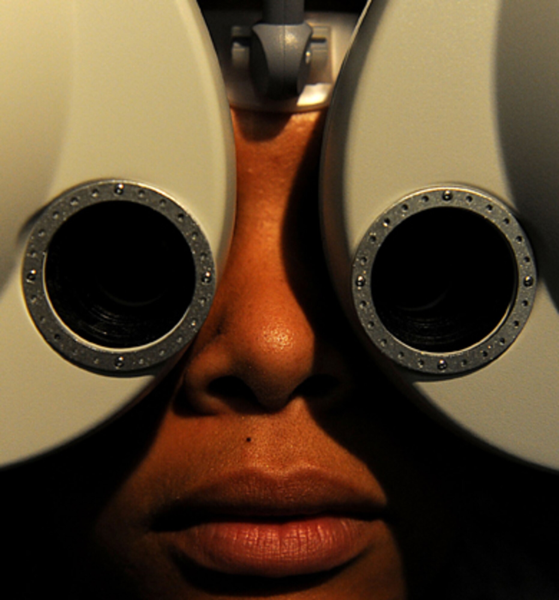 U.S. Air Force Staff Sgt. Suzette Skrecz, 18th Medical Support Squadron medical readiness technician, looks into a phoropter at the optometry clinic at Kadena Air Base Japan, Oct. 13, 2011. A phoropter is used to find the correct prescription for  a set of eyes by switching through different possibilities while the patient reads an eye chart on the other side of the room.  (U.S. Air Force photo by Airman 1st Class Brooke P. Beers/Released)