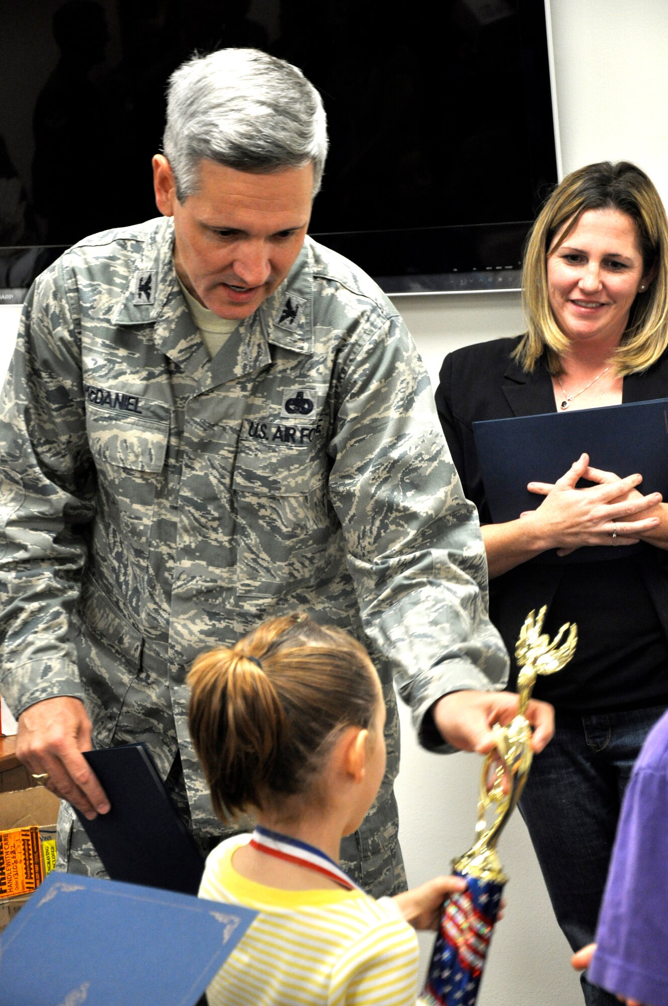 Col. Michael McDaniel, the 71st Mission Support Group commander at Vance Air Force Base, Okla., hands out trophies to the winners of the pie eating contest, ice cream eating contest and hula-hoop contest at the Month of the Military Family celebration held Nov. 18 in the Airman & Family Readiness Center. More than 140 folks attended the celebration, which included Home-Front-Hero medals presented to 38 children of 16 deployed Vance Airmen. The Month of the Military Family recognizes what families of military members go through when their loved ones are away from home serving their country. (U.S. Air Force photo/ Airman 1st Class Frank John Casciotta)