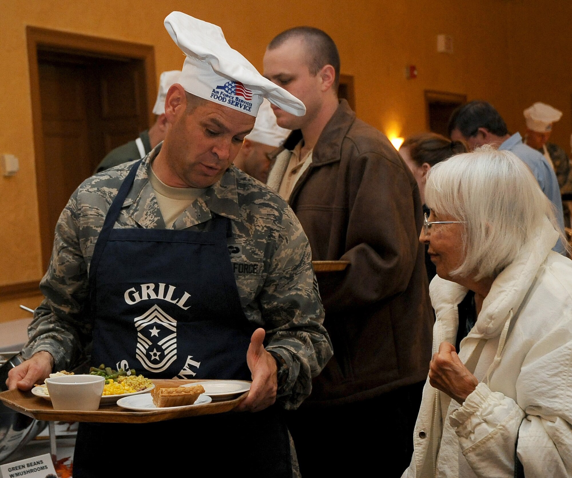 Chief Master Sgt. Larry Malcom, 2nd Bomb Wing command chief, assists a guest through the serving line at the Consolidated Club on Barksdale Air Force Base, La., Nov. 24. More than 20 base leaders volunteered to serve a large Thanksgiving meal to Barksdale Airmen, retirees and family members. (U.S. Air Force photo/Senior Airman Amber Ashcraft)(RELEASED)