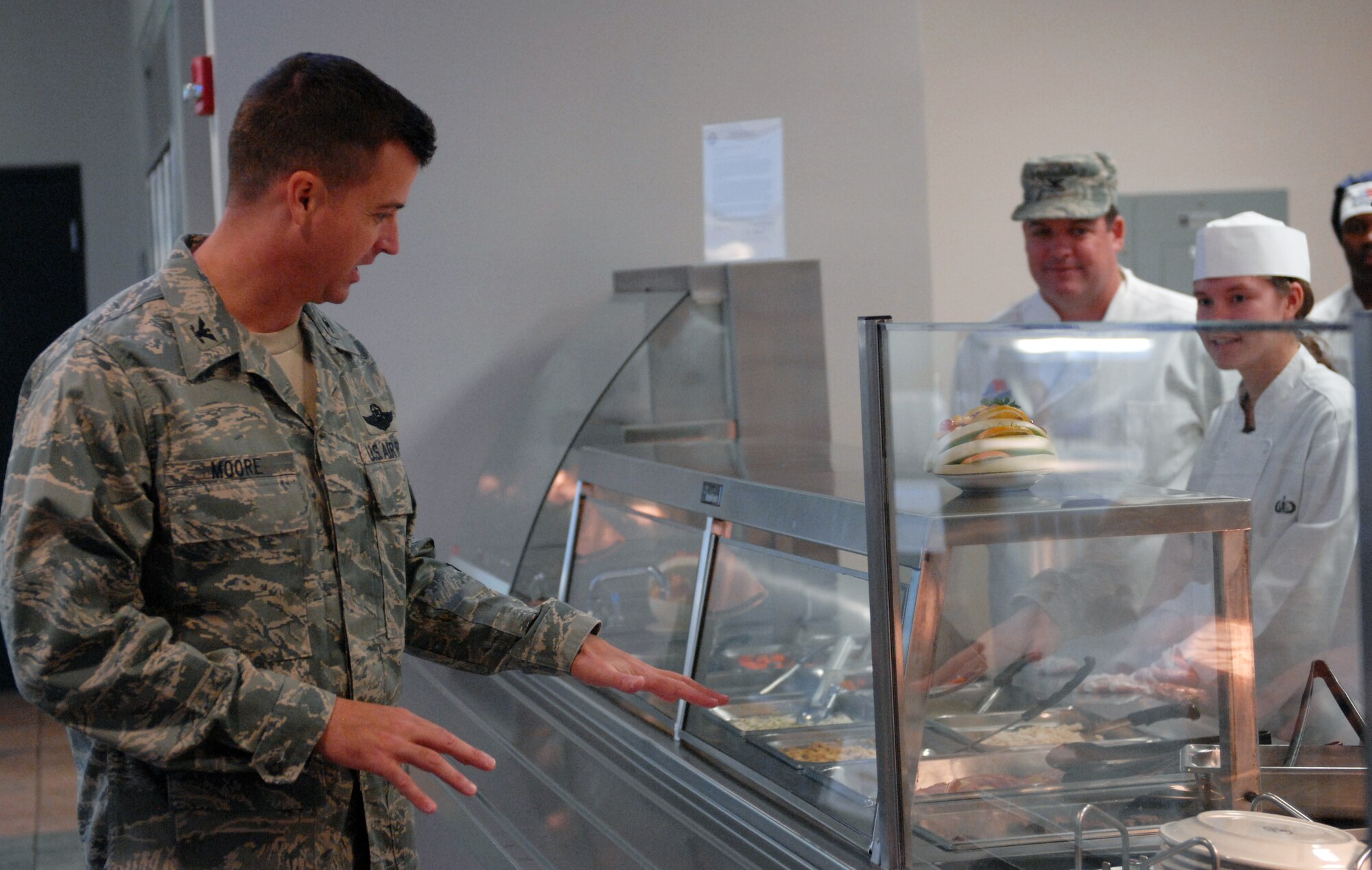 U.S. Air Force Col. Charlie Moore, 20th Fighter Wing commander, compliments the cooks for their hard work and food presentation, at Shaw Air Force Base, S.C., Nov. 24, 2011. Every year commanders and chief master sergeants volunteer to serve at the Shaw dining facility for those who could not make it home to family and friends for Thanksgiving. (U.S. Air Force photo by Airman 1st Class Blake Hubbard/Released)
