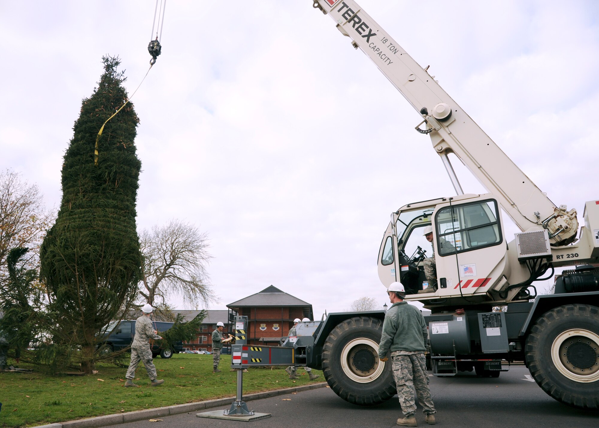 RAF MILDENHALL, England – Staff Sgt. Robert Hartless, 100th Civil Engineer Squadron (near crane), helps guides Master Sgt. Daniel Smith, 100th CES (driver), to lower a Christmas tree into place near the Bob Hope Community Center here Nov. 28, 2011. Electricians will install Christmas lights and decorations later in the day, lighting the way for a more joyous display for all Team Mildenhall to view. (U.S. Air Force photo/Tech. Sgt. Kevin Wallace)