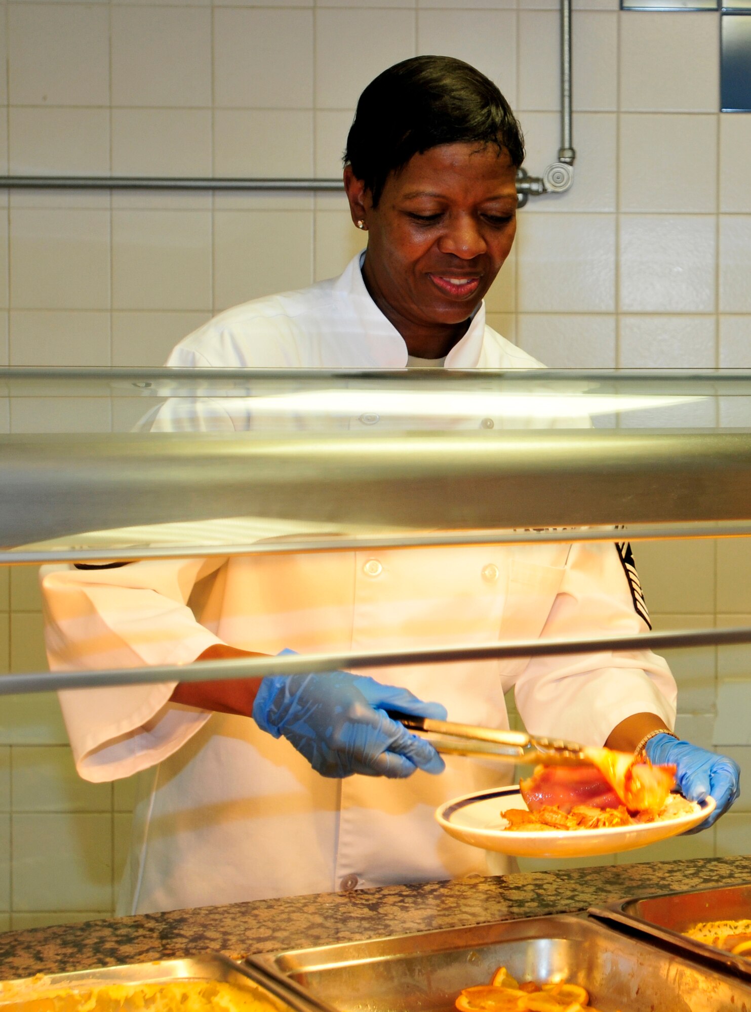 ROYAL AIR FORCE LAKENHEATH, England - Chief Master Sgt. SaRita Lathan, 48th Fighter Wing command chief, serves up a Thanksgiving meal at the Knight's Inn Dining Facility, Nov. 24, 2011. Each year, base leadership officials volunteer their time to serve Thanksgiving meals to Airmen, civilians and families. (U.S. Air Force photo by Senior Airman Tiffany M. Deuel)
