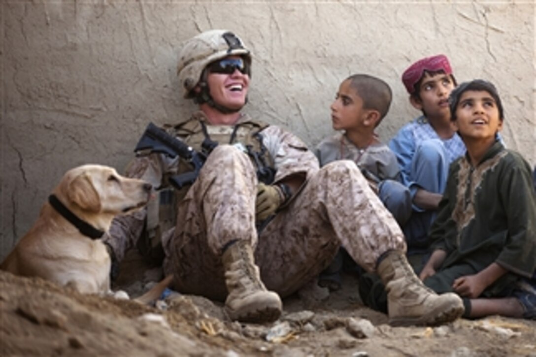 U.S. Marine Corps Lance Cpl. Isaiah Schult, an improvised explosive device dog handler, jokes with Afghan children and an Afghan National Police officer outside a local residence in Garmsir district, Helmand Province, Afghanistan, on Nov. 22, 2011.  Schult is assigned to Headquarters and Service Company, 3rd Battalion, 3rd Marine Regiment.  
