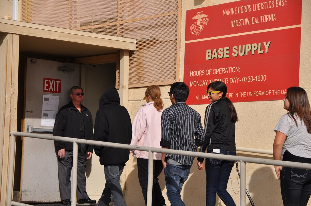 Members of the Mojave Express Logistics Academy from Barstow High School are greeted by Richard Green (left), supply officer, Marine Corps Logistics Base Barstow, as they filed into Warehouse 8, Nov. 28. The XP Academy offered the opportunity to the tenth grade students to learn what educational experience, skill sets and training they would need to get a high paying, local job after graduating from high school. Seniors with the XP Academy will get an opportunity to tour the Yermo Annex of MCLB Barstow at a later date.