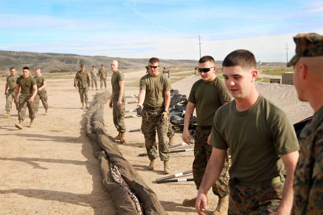 Command Element Marines with the 15th Marine Expeditionary Unit prepare to set up camouflage netting on tents for a Command Operations Center at the Command Post Exercise II on Camp Pendleton, Nov. 28. Command Post Exercise II focused on the unit’s ability to stand up an entire Command Operations Center quickly in the event the MEU is called to shore. Although the exercise included training for this specific event, CPEX II brought the Marines and sailors together by encouraging them to work as a team and build camaraderie among each other. (U.S. Marine Corps photo by Cpl. John Robbart III)