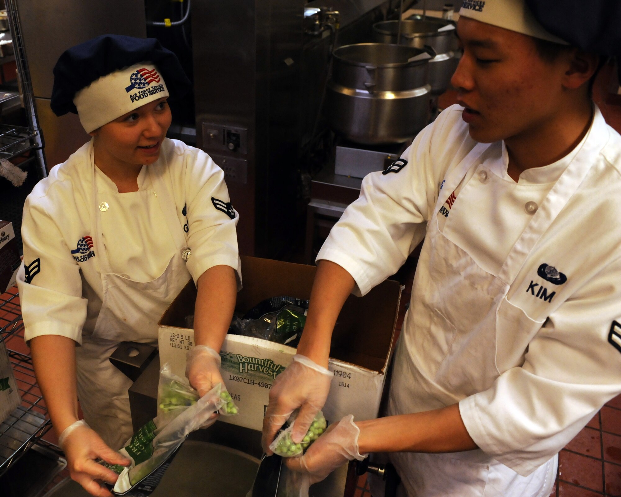 U.S. Air Force Airman 1st Class Brenna Grupe and Airman 1st Class Joon Kim, both from the 355th Force Support Squadron, pour green beans into a boiler in the Desert Dining Inn on Davis-Monthan Air Force Base, Ariz. Nov. 11, 2011. The meals prepared by the Desert Dining Inn staff served U.S. armed forces members, both past and present. (U.S. Air Force photo by Airman 1st Class Timothy D. Moore/Released)
