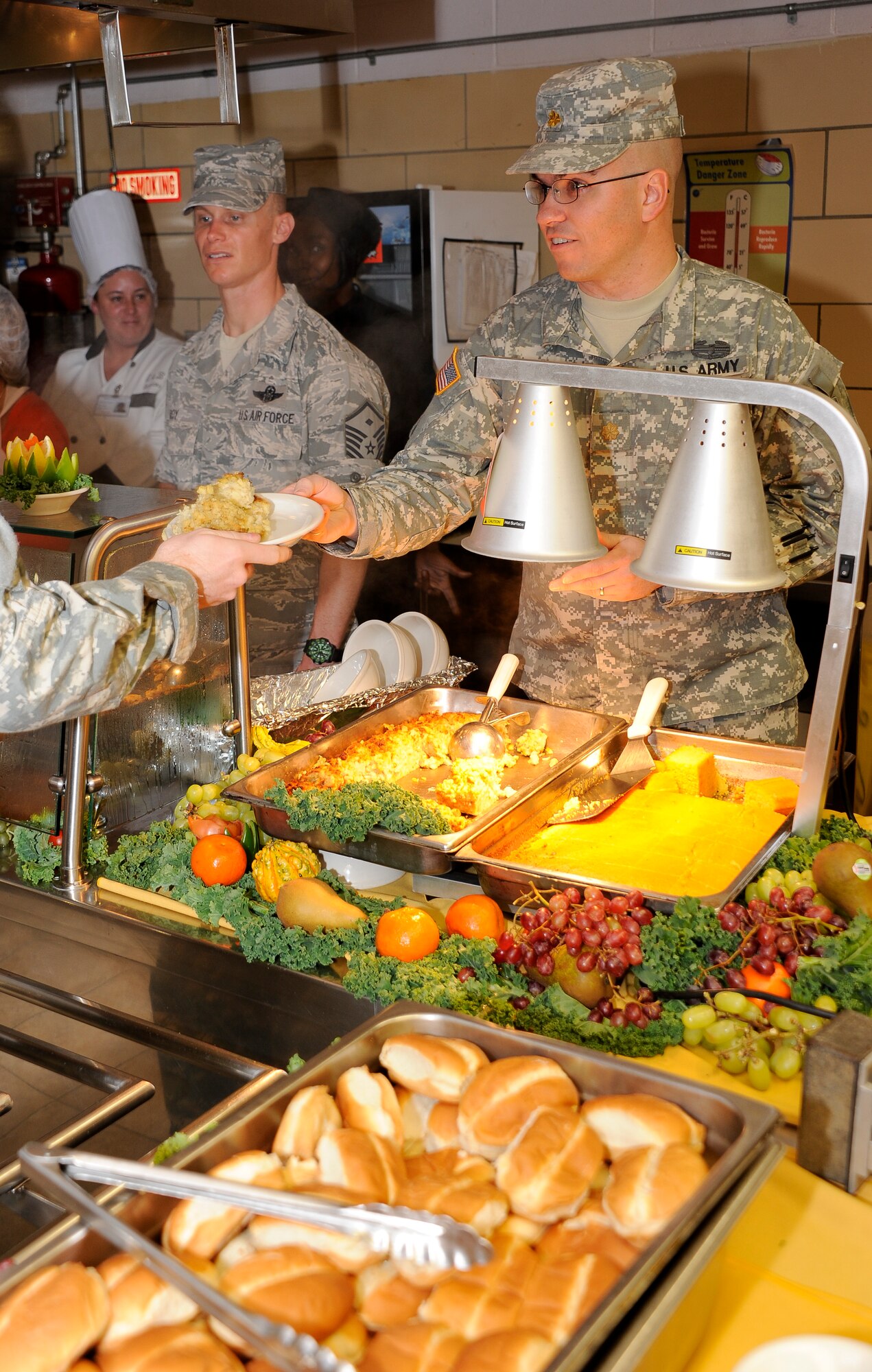 Master Sgt. Bryant Roy, U.S. Air Force Expeditionary Center first sergeant (left) and Maj. Bradford Cary, 1st Battalion, 1st Training Brigade battalion commander work the chow line during a Thanksgiving lunch Nov. 24. at the Dix Dining Facility. Senior leaders from across Joint Base McGuire-Dix-Lakehurst come together every year to show their gratitude for the work servicemembers do here. (U.S. Air Force photo by Airman 1st Class Bryan Swink/Released)