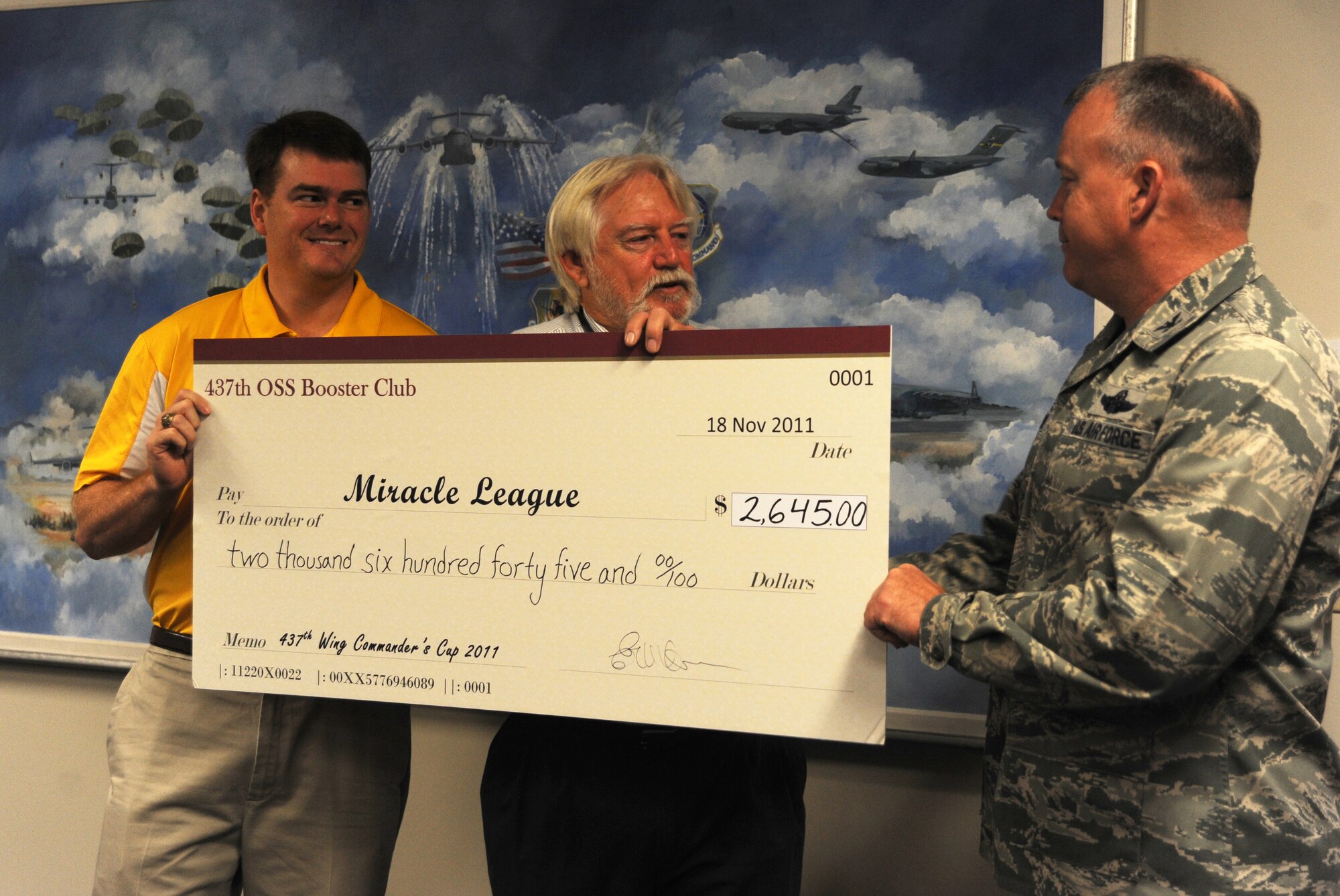 Colonel Erik Hansen presents a check to the Charleston Miracle League Nov.23 for the amount of $2,645 which was raised during the Commander's Cup Golf Tournament at Joint Base Charleston - Air Base. The Charleston Miracle League is a baseball league for special needs children. Hansen is the Commander of the 437th Airlift Wing. (U.S. Air Force photo/Airman 1st Class Ashlee Galloway)