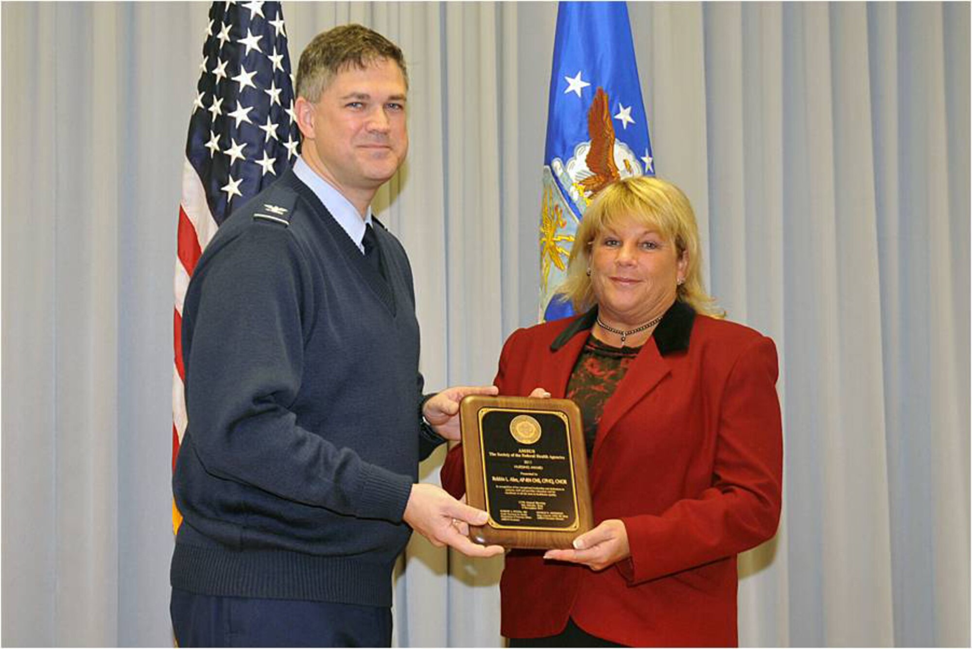 Col. Kevin Dixon, 55th Wing vice commander, presents Robbin Alex, 55th Medical Group chief of quality services, with the Association of Military Surgeons of the United States nurse of the year award at the wing staff meeting on Nov. 14 at the 55th Operations Support Squadron auditorium. As the chief of quality services, Alex is directly responsible for the group's entire health services compliance inspection program. (Air Force photo by Jeff Gates)