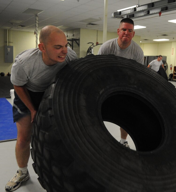 U.S. Air Force Senior Airman Chris Koelndorfer, 1st Maintenance Squadron line delivery and ammo specialist, and Senior Airman Christopher Kelly, 1st MXS maintenance crew chief, flip a tire during a physical training session at Langley Air Force Base, Va., Nov. 22, 2011. The unit’s twice a week PT session gives Airmen unique workout options with inventive activities, including tire flipping, sled pushes and parachute sprints. (U.S. Air Force Photo by Airman 1st Class Racheal Watson/Released)