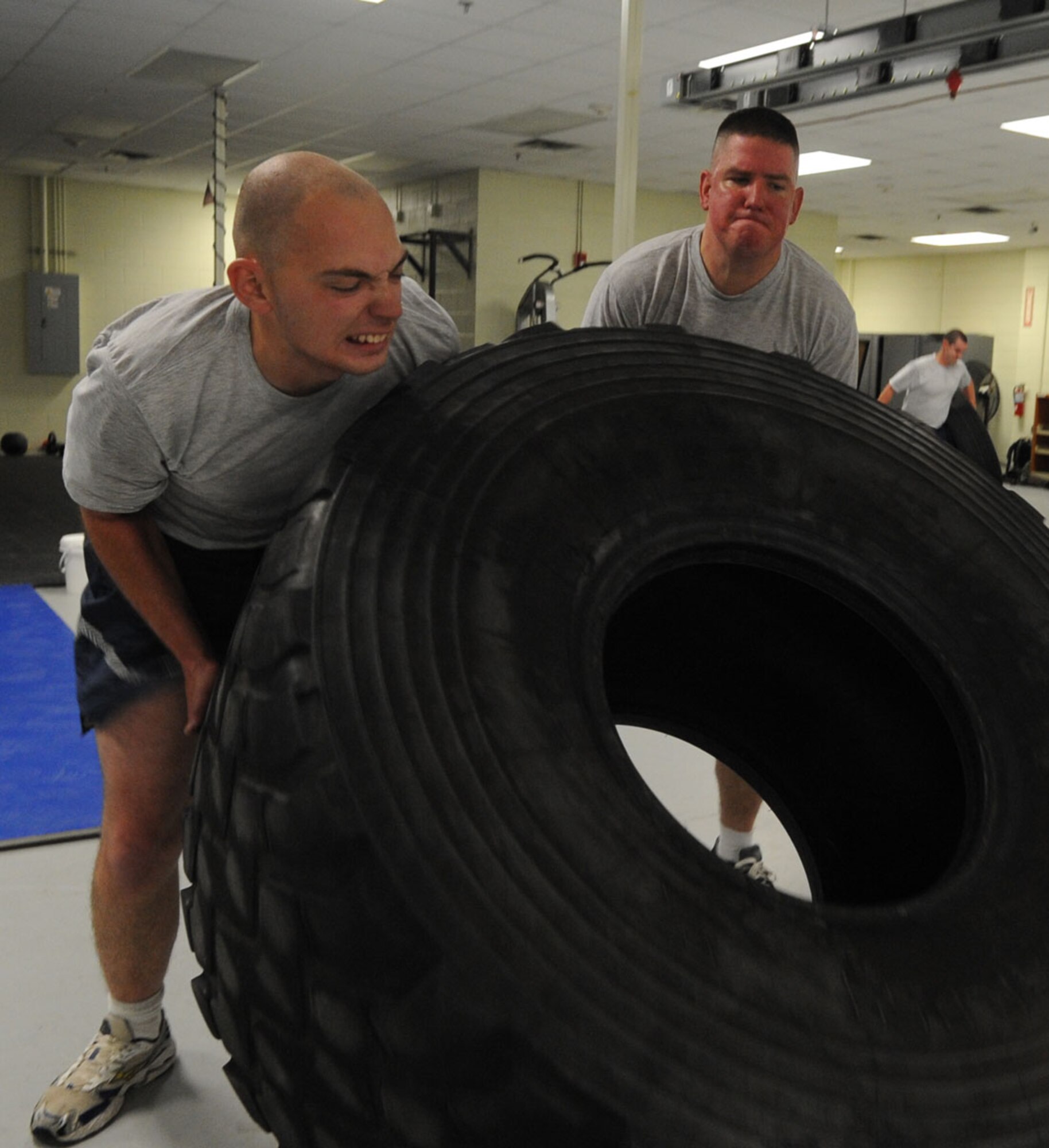 U.S. Air Force Senior Airman Chris Koelndorfer, 1st Maintenance Squadron line delivery and ammo specialist, and Senior Airman Christopher Kelly, 1st MXS maintenance crew chief, flip a tire during a physical training session at Langley Air Force Base, Va., Nov. 22, 2011. The unit’s twice a week PT session gives Airmen unique workout options with inventive activities, including tire flipping, sled pushes and parachute sprints. (U.S. Air Force Photo by Airman 1st Class Racheal Watson/Released)