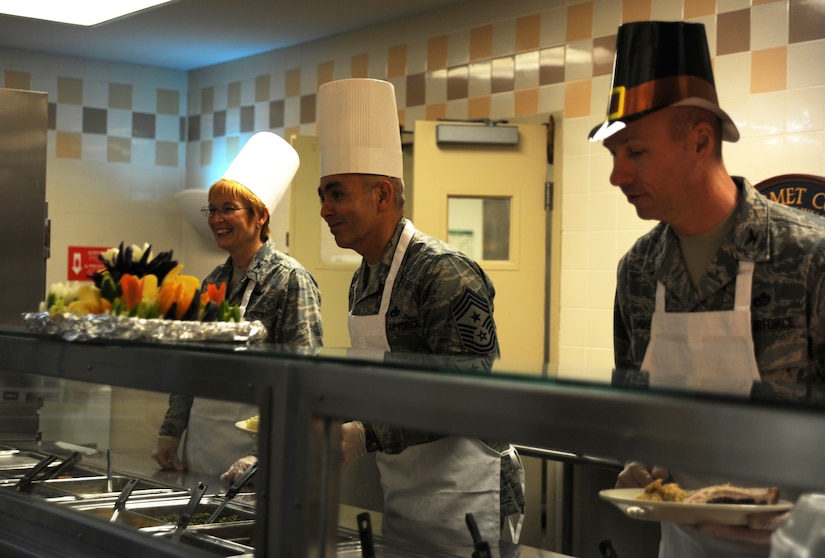 Colonel Judith Hughes, Chief Master Sgt. Jose LugoSantiago and Col. Justin Davey serve Thanksgiving dinner to Airmen and retirees at the Joint Base Charleston Dining Facility at JB Charleston Air Base  Nov. 24. Unit commanders, chiefs and their families took time out of their own Thanksgiving festivities to serve their fellow Airmen and retirees. Hughes is the 628th Medical Group commander, LugoSantiago is the 628th Air Base Wing command chief and Davey is the 628th Mission Support Group commander. (U.S. Air Force photo/Airman 1st Class Ashlee Galloway)