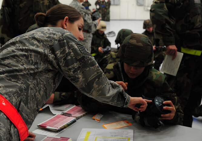 Technical Sgt. Karen Harris explains how to inspect the air filter on a gas mask to Airman 1st Class Sebastiana Solis-Lopez during the Ability To Survive and Operate Rodeo a Nose Dock One at Joint Base Charleston - Air Base Nov. 28. The rodeo was held to help prepare more than 700 Airmen for the upcoming JB Charleston Operational Readiness Inspection. The rodeo included  Self Aid Buddy Care, weapons familiarization, Unidentified Explosive Objects training and donning chemical protection gear.  Harris is from the 628th Civil Engineer Squadron and Solis-Lopez is from the 437th Aircraft Maintenance Squadron.  (U.S. Air Force photo/ Staff Sgt. Nicole Mickle)  