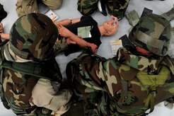 Mock deployers perform Self Aid Buddy Care on a simulated victim during the Ability To Survive and Operate Rodeo at Nose Dock One at Joint Base Charleston - Air Base Nov. 28.   The rodeo was held to help prepare more than 700 Airmen for the upcoming JB Charleston Operational Readiness Inspection. The rodeo included  Self Aid Buddy Care, weapons familiarization, Unidentified Explosive Objects training and donning chemical protection gear.   (U.S. Air Force photo/ Staff Sgt. Nicole Mickle)  