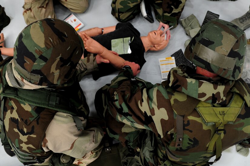 Mock deployers perform Self Aid Buddy Care on a simulated victim during the Ability To Survive and Operate Rodeo at Nose Dock One at Joint Base Charleston - Air Base Nov. 28.   The rodeo was held to help prepare more than 700 Airmen for the upcoming JB Charleston Operational Readiness Inspection. The rodeo included  Self Aid Buddy Care, weapons familiarization, Unidentified Explosive Objects training and donning chemical protection gear.   (U.S. Air Force photo/ Staff Sgt. Nicole Mickle)  