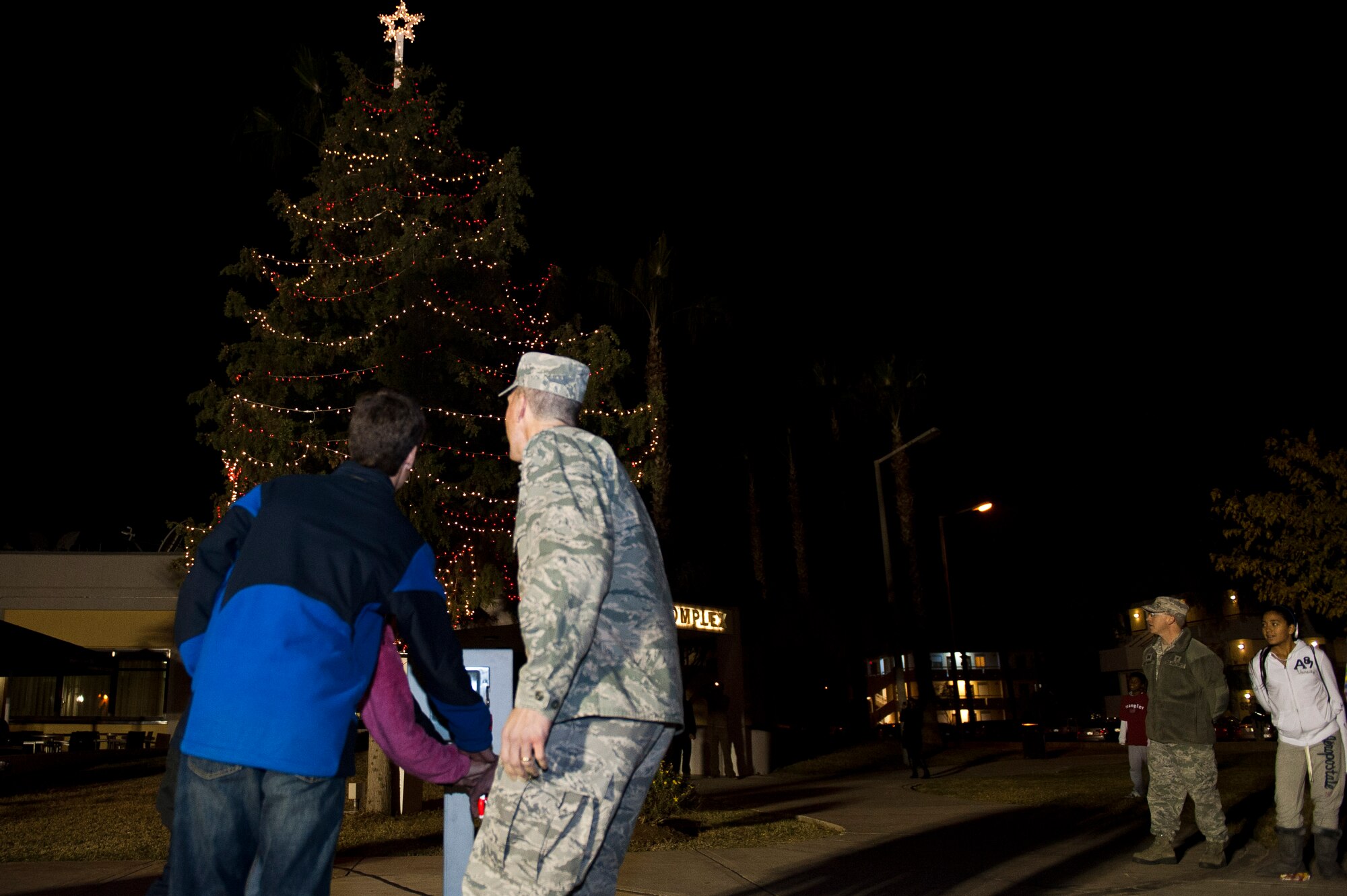 Col. Chris Craige, 39th Air Base Wing commander, and his children flip the switch to light the holiday tree ouside the Club Complex during the base tree lighting ceremony Nov. 28, 2011, at Incirlik Air Base, Turkey. The Incirlik Elementary School choir performed and Santa Claus arrived on a fire truck during the event. (U.S. Air Force photo by Senior Airman Anthony Sanchelli/Released)