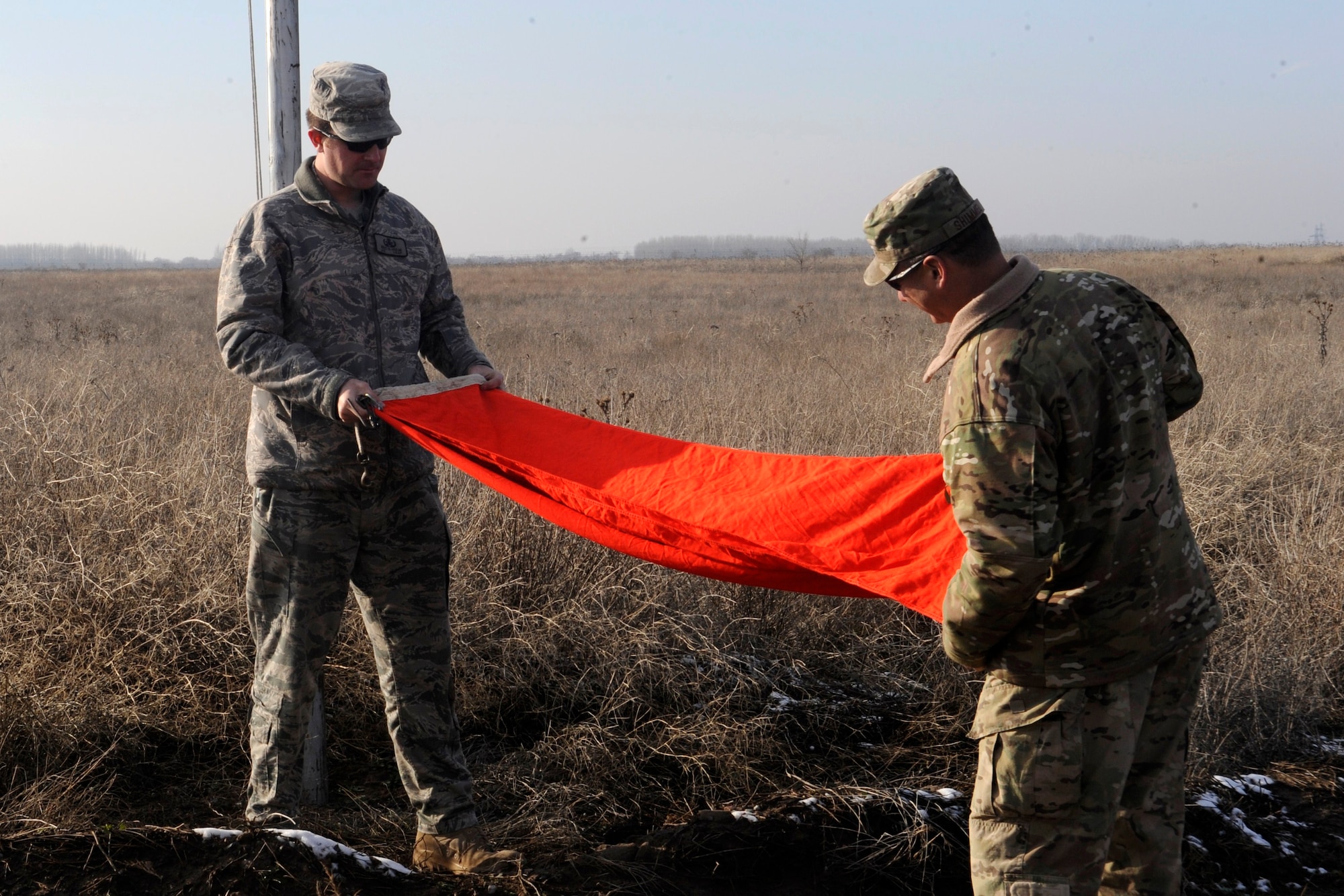Airman 1st Class Eric Holm (left) and Chief Master Sgt. Mitchell Shimmel fold the active range flag after a controlled detonation at the explosive ordnance disposal range at the Transit Center at Manas, Kyrgyzstan, Nov. 29, 2011.  Holm is a 376th Expeditionary Civil Engineer Squadron EOD technician deployed from Mountain Home Air Force Base, Idaho. Shimmel is an EOD chief returning to Eglin AFB, Fla., from a deployment to Camp Leatherneck, Afghanistan. (U.S. Air Force photo/Tech. Sgt. Tammie Moore)