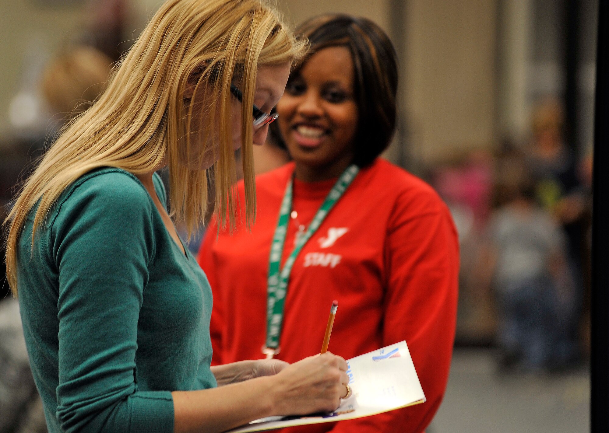 Cam Bankhead, child care coordinator for the Sumter YMCA, looks on as Emily Applegate, wife of Airman 1st Class Zachary Applegate, 20th Equipment Maintenance Squadron, fills out a form to be entered into a YMCA raffle during a military family appreciation event hosted by Shaw?s Airman and Family Readiness Center, Nov. 29, 2011, Shaw Air Force Base, S.C. November marks military family appreciation month and to show their appreciation, the 20th Force Support Squadron Airman and Family Readiness Center organized an event which brought out several local Sumter vendors There were more than 14 different vendors that provided military members and their families with free information and products. (U.S. Air Force photo by Senior Airman Kenny Holston/Released)


