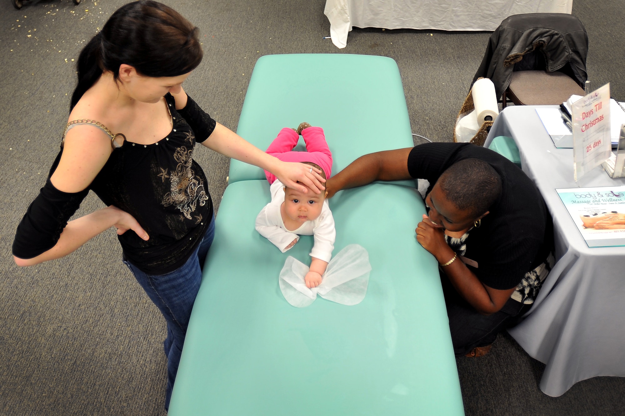 Betty Braxton watches as Aria Baxton, (center) daughter of Senior Airman Lawrence Baxton, 609th Air and Space Operations Center Detachment 1, receives a baby massage from Tiffany Johnson, massage therapist with Body and Sole, during a military family appreciation event hosted by Shaw?s Airman and Family Readiness Center, Nov. 29, 2011, Shaw Air Force Base, S.C. November marks military family appreciation month and to show their appreciation, the 20th Force Support Squadron Airman and Family Readiness Center organized an event which brought out several local Sumter vendors. There were more than 14 different vendors that provided military members and their families with free information and products. (U.S. Air Force photo by Senior Airman Kenny Holston/Released)


