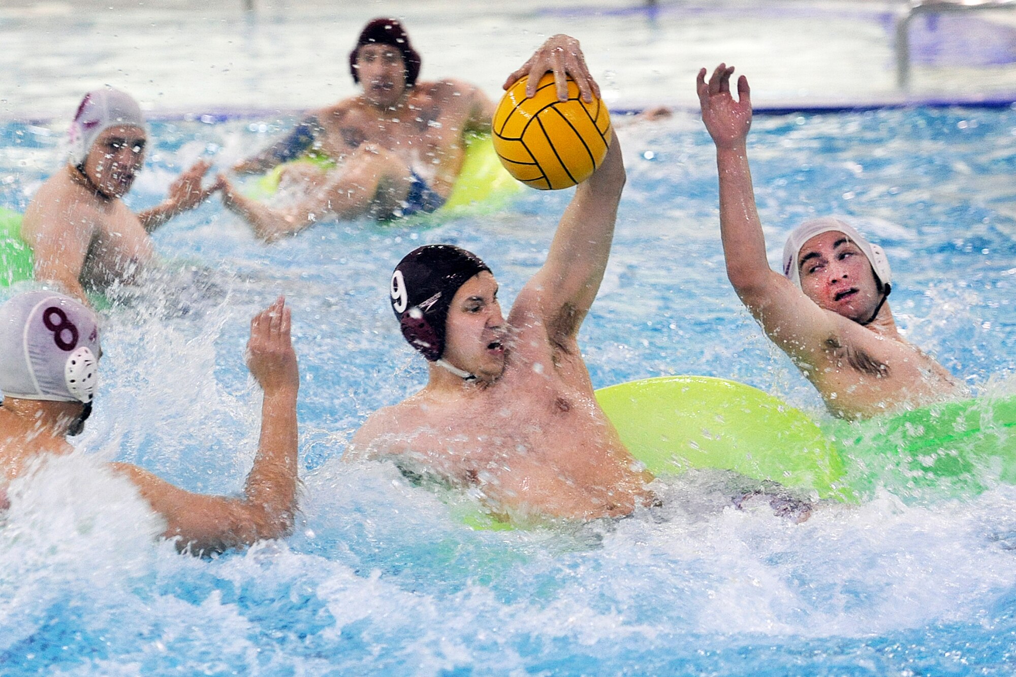 Josh Earle, 95th Chemical Company, maneuvers through the C Company, 307th Expeditionary Signal Battalion defense in Joint Base Elmendorf-Richardson inner tube water polo tournament action Nov. 23 in the Buckner Physical Fitness Center pool. The 95th cruised to a 26-10 victory and advanced to the championship game against the 673d Force Support Squadron. (U.S. Air Force photo/John Pennell)