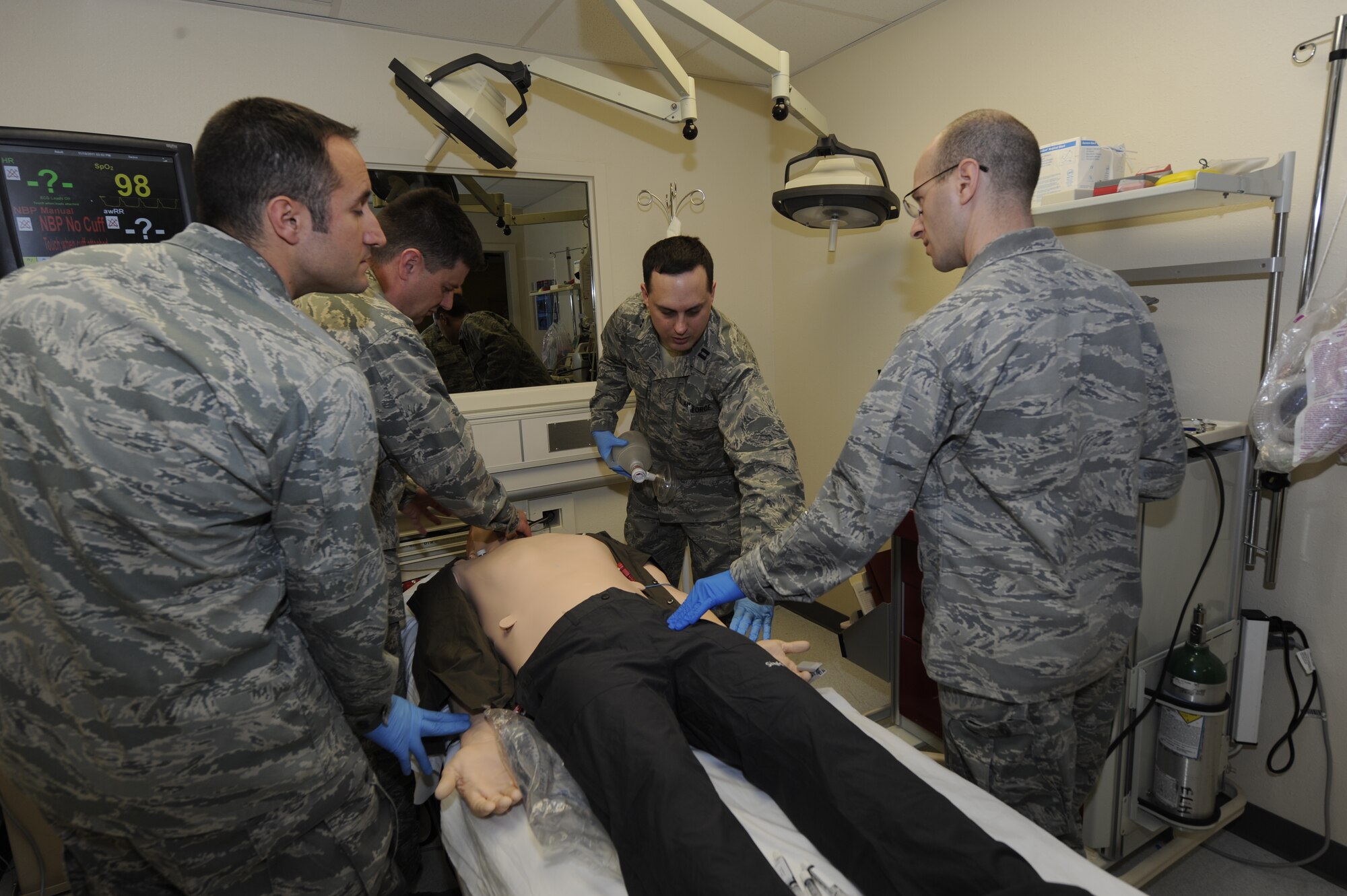 Medical students feel for the "patient’s” pulse during a training scenario simulating a medical emergency at the 673d Medical Group Simulation Center Nov. 10, 2011. The students come from a variety of medical departments to get the realistic practice. The "patient" is a high-tech manikin called SimMan equipped to simulate every sign and symptom a real patient would display, including multiple locations to detect a pulse. The training is performed with an instructor observing through a two-way mirror and recorded using action-by-action video and data collected using a Wi-Fi network. (U.S. Air Force photo/Staff Sgt. Robert Barnett)