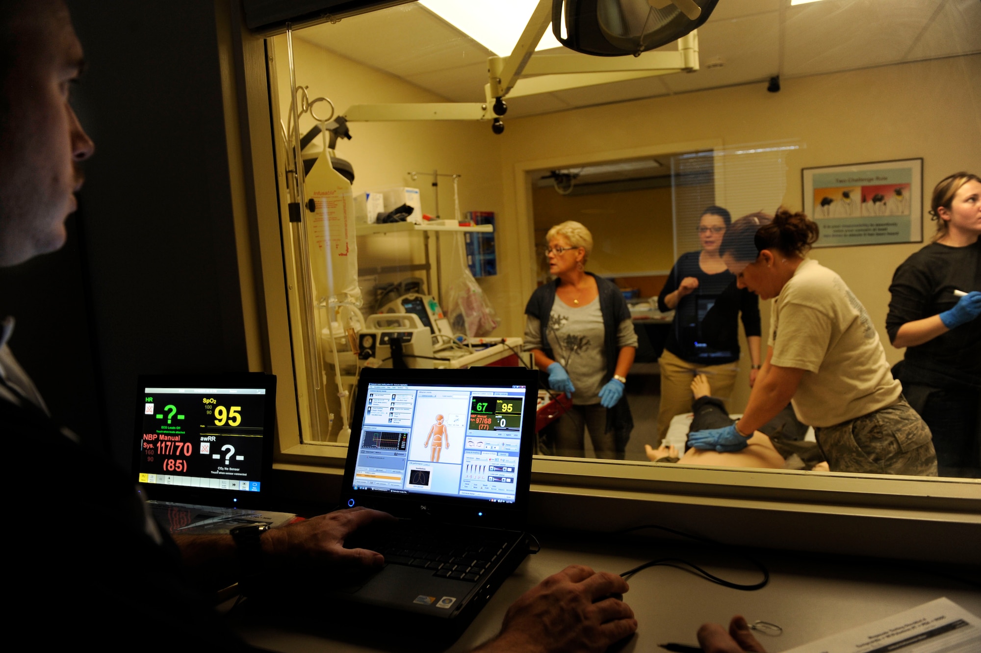 Will Enfinger operates the "patient" from the control room while medical students practice treating ailments such as cardiac arrest during a training scenario simulating a medical emergency at the 673d Medical Group Simulation Center Nov. 10, 2011. The students come from a variety of medical departments to get the realistic practice. The "patient" is a high-tech manikin called SimMan equipped to simulate every sign and symptom a real patient would display. The training is performed with an instructor observing through a two-way mirror and recorded using action-by-action video and data collected using a Wi-Fi network. (U.S. Air Force photo/Staff Sgt. Robert Barnett)
