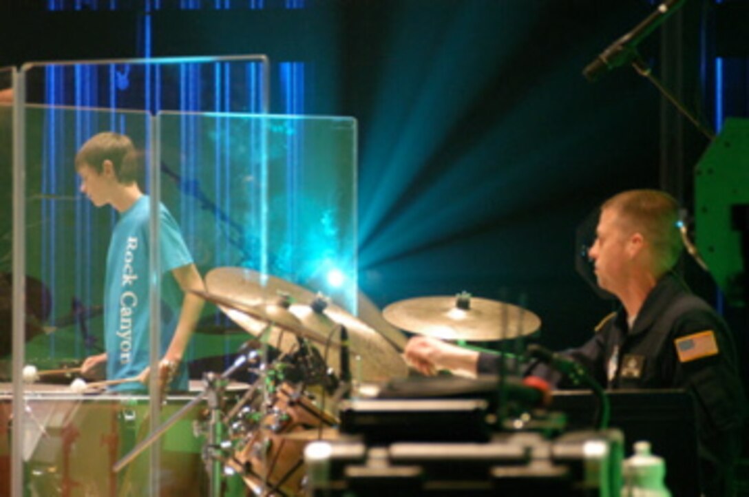 Blue Steel from the United States Air Force Academy Band performs with the Rock Canyon High School Orchestra in Lone Tree, Colorado. In this photo, MSgt Chris Gaona is playing the drumset while a student percussionist from Rock Canyon High School plays timpani in the background.