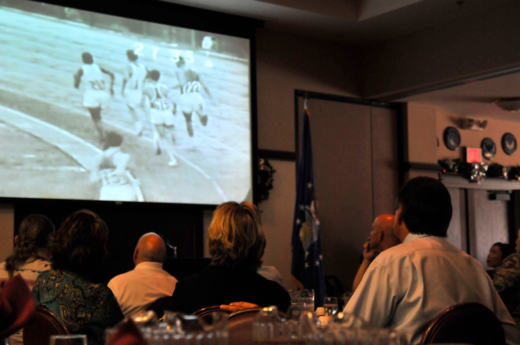 Airmen attending the Native American Heritage Luncheon watch a video of 1964 Olympic Gold Medalist Billy Mills, a Native American and the only American ever to win the 10,000 meter Olympic race, before his presentation at the Recce Point Club on Beale Air Force Base, Calif. Nov 29, 2011.  (U.S. Air Force photo by Staff Sgt. Jeremy McGuffin/Released)