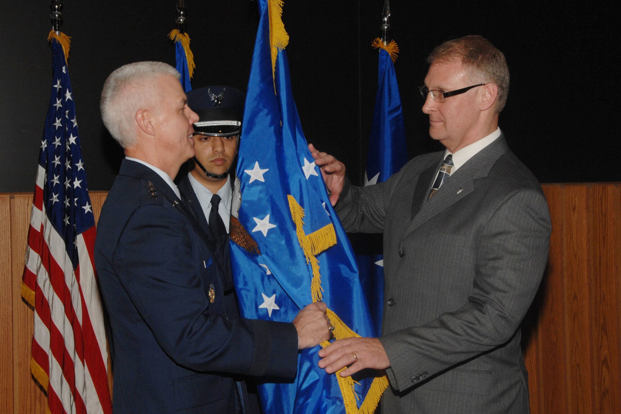 HANSCOM AIR FORCE BASE, Mass. – John Lyle (right), director of Contracting, accepts the Senior Executive Service flag from Lt. Gen. CR Davis, Electronic Systems Center commander, during his promotion to SES Nov. 22. Lyle previously served as ESC Contracting director from 2004 to 2006 before retiring from the Air Force as a colonel. (U.S. Air Force photo by Linda LaBonte Britt)